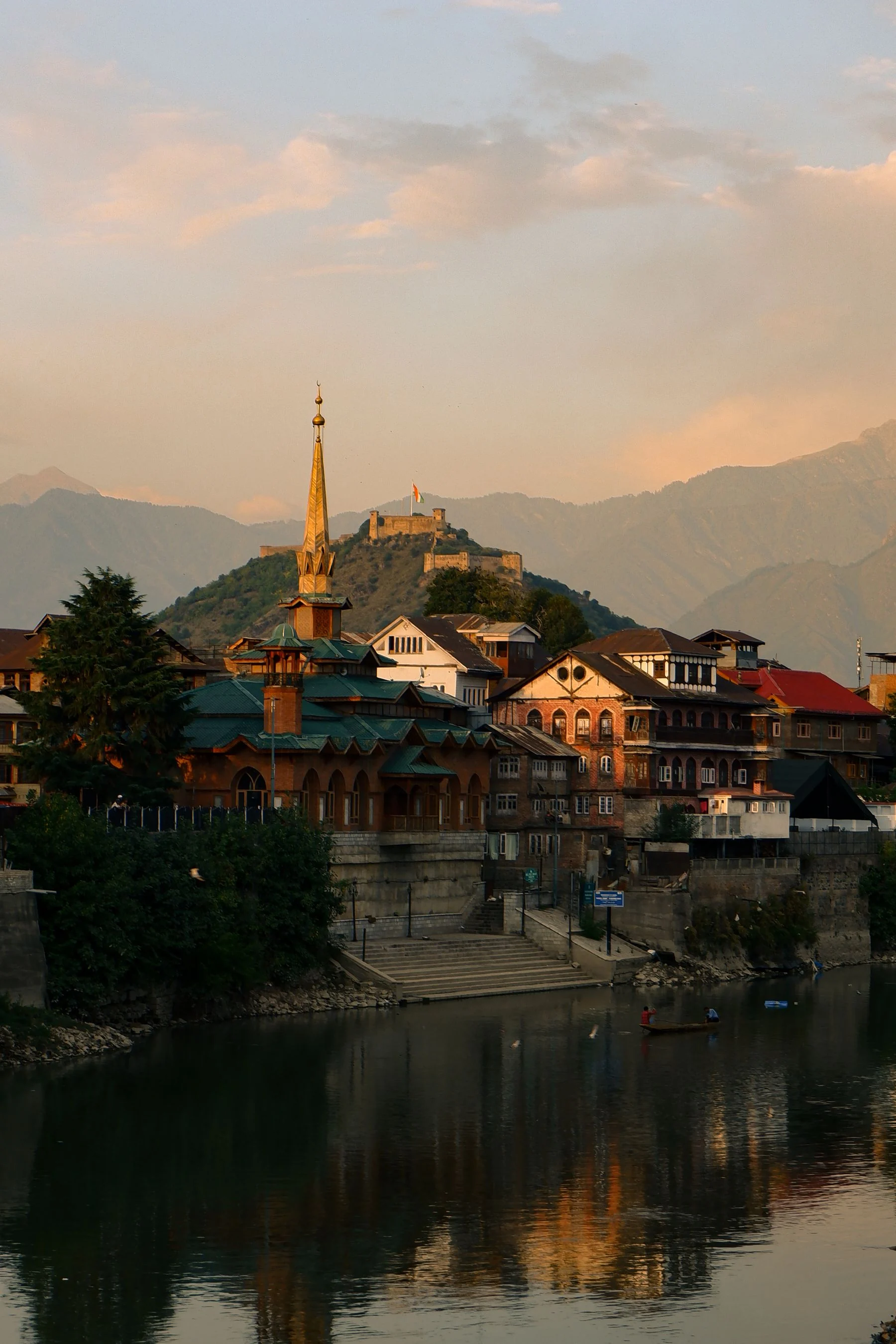 Historic Srinagar waterfront architecture reflected in the water, with the mountains of Kashmir beyond